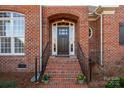 Inviting brick home entrance with arched doorway, black door, and wrought iron railings on brick steps at 8018 Cotton St, Harrisburg, NC 28075