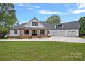 Charming exterior elevation of a farmhouse-style home with a three car garage and large front yard at 106 Beachview Dr, Mooresville, NC 28117