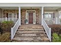 Inviting front porch with stone steps, white railings, and a stylish stone and siding facade at 10823 Caverly Ct, Huntersville, NC 28078