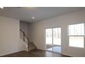 Open-concept living room with wood floors, sliding glass doors, and staircase access to the upper level at 3427 Secrest Lndg, Monroe, NC 28110