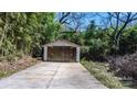 Detached garage surrounded by lush greenery, featuring a concrete driveway and wooden doors at 624 Harris Nw St, Concord, NC 28025