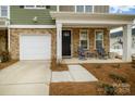 Inviting front porch with stone accents, a black front door, and chairs, offering a cozy outdoor space at 8157 Merryvale Ln, Charlotte, NC 28214