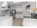Bright kitchen with white cabinetry, stainless steel appliances, mosaic backsplash, and tile flooring, offering a modern design at 8932 Raven Park Dr, Charlotte, NC 28216