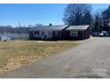 A spacious single-story home with a metal roof and ample yard space on a sunny day at 920 Oakridge Farm Hwy, Mooresville, NC 28115