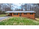 Charming red brick home featuring a metal roof, black shutters, and well-maintained landscaping at 104 Pop Davis Rd, Taylorsville, NC 28681