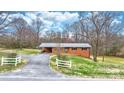 Inviting brick home with a metal roof, carport, white picket fence, and a well-manicured lawn at 104 Pop Davis Rd, Taylorsville, NC 28681
