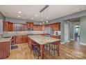 Open kitchen with wood cabinetry, stainless appliances, granite counters, and island seating at 158 Crimson Orchard Dr, Mooresville, NC 28115