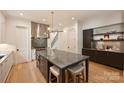 Open kitchen with an expansive island, sleek lighting, stainless steel range hood and hardwood floors at 238 Laurel S Ave # B, Charlotte, NC 28207