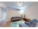 Bright living room with stylish gray sofa, cozy blue chair, ceiling fan, and leafy area rug at 333 W Trade St # 2503, Charlotte, NC 28202