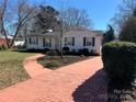 Well kept home featuring a brick walkway, complemented by lush landscaping and mature trees at 3240 Sunset Dr, Charlotte, NC 28209