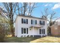 Beautiful two-story home featuring a white brick facade, black shutters, and mature trees in the front yard at 5717 Ruth Dr, Charlotte, NC 28215