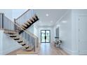 Hallway with light wood floors and staircase with black metal railings and a view to the outdoors at 5834 Five Knolls Dr, Charlotte, NC 28226