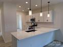 Modern kitchen boasts white cabinets, quartz countertops, stainless steel appliances, and stylish pendant lighting at 1120 Red River Rd, Salisbury, NC 28144