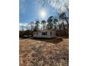 Quaint single-story home with light gray siding, mature trees, and a lush natural landscape at 3437 Wilkesboro Hwy, Statesville, NC 28625
