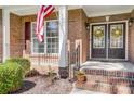 Inviting front porch with American flag, brick columns and double front doors at 5601 Turkey Oak Dr, Mint Hill, NC 28227