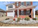 Charming two-story brick home featuring a well-manicured lawn, covered porch, and attached two-car garage at 815 Oak Embers Se Dr, Concord, NC 28025