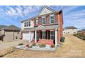 Beautiful two-story home featuring a brick exterior, attached garage, and landscaped yard with decorative elements at 815 Oak Embers Se Dr, Concord, NC 28025