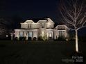 Eye-catching two-story brick home with exterior lighting, highlighting its architectural details and curb appeal at night at 1005 Cherry Laurel Dr, Waxhaw, NC 28173