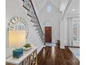 Elegant foyer with hardwood floors, a curved staircase, and a decorative mirror creating a grand entrance at 13500 Robert Walker Dr, Davidson, NC 28036