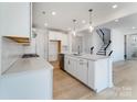 Contemporary white kitchen with an island, stainless steel appliances, and light wood flooring at 136 Glenn Dr, Mooresville, NC 28115