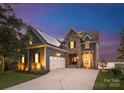Stunning two-story home with stone accents, solar panels and a spacious driveway at dusk at 21013 Island Forest Dr, Cornelius, NC 28031