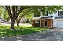 Charming two-story home featuring a brick facade, green lawn and mature tree at 303 Cupped Oak Ct, Charlotte, NC 28213