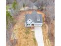 Aerial view of a charming white home with a gray roof, front-facing garage, and long driveway on a wooded lot at 5101 Thornhill Dr, Gastonia, NC 28052