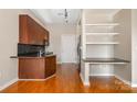 Kitchen featuring warm wood cabinets, granite countertops, and open shelving for storage at 525 E Sixth St # 208, Charlotte, NC 28202