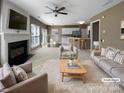 Bright open-plan living room featuring a fireplace, ceiling fan, and connection to kitchen at 9139 Hearst Ct, Charlotte, NC 28269