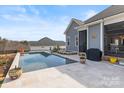 Backyard showcases an inviting pool, spa, grill, and elegant travertine patio at 107 Hillside Cove Ct, Mooresville, NC 28117
