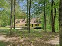 Exterior showcasing a yellow two-story home surrounded by trees, with an attached garage and inviting front porch at 124 Canterbury Ln, Matthews, NC 28104