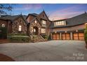 Beautifully lit home with stone and brick facade, showcasing the garage and driveway at 1312 Lookout Cir, Waxhaw, NC 28173