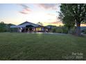 Ranch home featuring an expansive lawn, carport, and picturesque mountain views during a tranquil sunset at 6285 Nc 16 N Hwy, Taylorsville, NC 28681