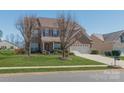 Inviting two-story brick home with mature trees and a green lawn, blending curb appeal with a comfortable setting at 10406 Little Whiteoak Rd, Charlotte, NC 28215