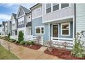 Charming two-story townhouse showcasing blue and gray siding, complemented by a landscaped front yard and white picket fence at 1270 Brawley School Rd # E, Mooresville, NC 28177