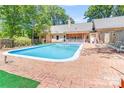 Large backyard pool surrounded by red brick and various seating areas at 1359 Carmen Ln, Gastonia, NC 28054