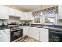 Well-lit kitchen featuring white cabinets, stainless steel appliances, and a double sink overlooking outdoors at 1911 Woodlawn St, Kannapolis, NC 28083