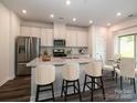 Open kitchen with white cabinets, island with seating, and stainless steel appliances at 2108 Morgan Hills Dr, Albemarle, NC 28001