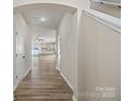 Inviting hallway with wood-look flooring, neutral paint, and arched entryway leading to the kitchen at 2124 Clapham Ct, Charlotte, NC 28215