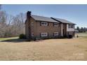 View of the side and front of a brick home, with a spacious lawn and mature trees at 257 Hickory Hill Ln, Stanley, NC 28164