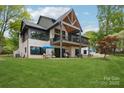 The backyard shows the 2-story home with outdoor seating, large yard, and mature trees at 121 Kelly Point Ln, Mooresville, NC 28117