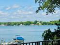 Beautiful lake view featuring a boat under a blue cover on a lift in front of a treelined shore with blue sky at 121 Kelly Point Ln, Mooresville, NC 28117