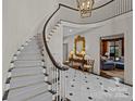 A grand foyer showcasing a curved staircase, marble floors, and elegant furnishings with high-end finishes at 1414 Biltmore Dr, Charlotte, NC 28207