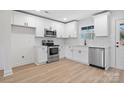 Modern kitchen featuring white cabinets, stainless steel appliances, and wood-look flooring at 211 E Rice St, Landis, NC 28088