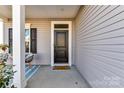 Inviting front door with a 'hello' doormat, surrounded by neutral siding at 3180 Streamside Dr, Davidson, NC 28036