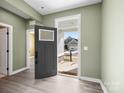 Welcoming foyer with an open door, light green walls, and durable laminate flooring throughout at 6420 Cambridge Dr, Harrisburg, NC 28075