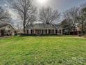 Wide view of a brick home featuring a lush green lawn and mature trees at 1030 Bolling Rd, Charlotte, NC 28207