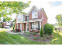 Two-story brick home with well-maintained lawn, porch with rocking chairs, and mature trees providing shade at 10836 Clark St, Davidson, NC 28036