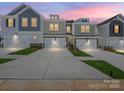 Twilight view of new construction townhomes with craftsman exteriors, attached garages, and manicured lawns at 109 Alluvium Ln, Waxhaw, NC 28173