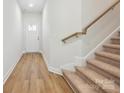 Bright hallway with wood-look flooring and staircase with carpeted treads and wood railing at 109 Alluvium Ln, Waxhaw, NC 28173